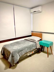 本图贡萨尔维斯Apartamento Artístico - Garagem - Ar Condicionado - Excelente Localização的一间卧室配有一张床和一张蓝色的桌子