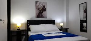 里奥阿查La Marina -Apartamentos frente al mar的一间卧室配有一张带蓝色毯子和两盏灯的床。