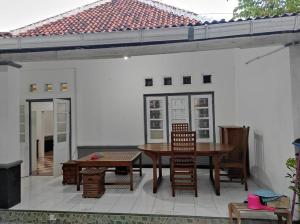 TimuranIin Homestay Jogja by We Stay的一个带桌椅的庭院和一座建筑