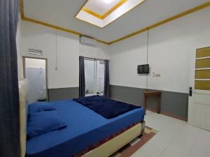 TimuranIin Homestay Jogja by We Stay的一间卧室配有蓝色的床和电视