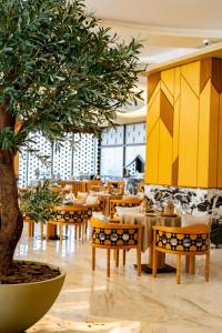 沙迦Luxe Grand Hotel Apartments的中间有桌子和树的餐厅