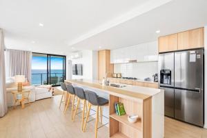 黄金海岸Luxury Ocean View Apartment的厨房配有带椅子和台面的岛屿