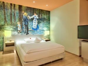 萨尔布吕肯Hotel Am Triller - Hotel & Serviced Apartments的卧室配有一张床,墙上挂有绘画作品