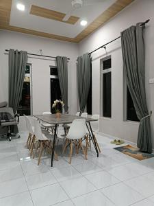 PendangAila Homestay Pendang的一间带木桌和椅子的用餐室