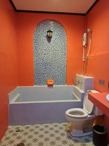 拉差汶里The Sun resort Ratchaburi的橙色的浴室设有浴缸和卫生间。