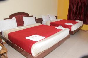 科代卡纳尔RPM Residency的两张位于酒店客房的床铺,配有红色床单
