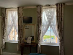 惠特比The Captain's Lodge accommodation的客房设有2扇窗户、1张桌子和1面镜子
