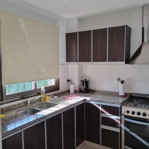门多萨Luminoso departamento en zona residencial的厨房配有水槽和炉灶 顶部烤箱