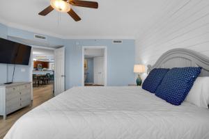 沃尔顿堡滩Heron 507- A Wave From It All的卧室配有白色床、蓝色枕头和吊扇