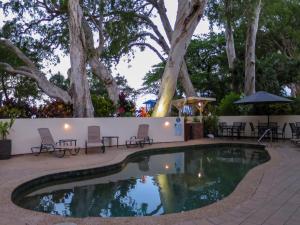 棕榈湾马林水域海滨公寓 的一个带桌椅和树木的游泳池