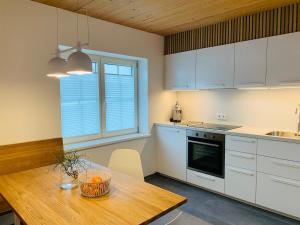 米特尔贝格Dorf(er)leben Ferienwohnung im Kleinwalsertal的厨房配有白色橱柜和木桌