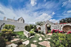 洛科罗通多Trulli Arco Antico的庭院里一座石头建筑,花朵花