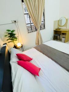 瓜埠QV Residence Langkawi - Jacuzzi, BBQ, & Steamboat的一间卧室配有一张带两个红色枕头的床