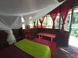 科克莱斯Finca Valeria Treehouses Glamping的一间卧室配有一张绿色的床和一张桌子