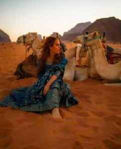 瓦迪拉姆Wadi Rum Meteor camp的坐在沙漠中的女人,带着骆驼