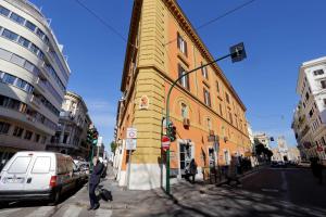 罗马La Flavia Design City Suites Rome的穿过黄色建筑前的街道的人