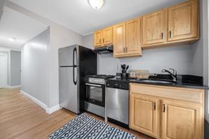 波士顿Easy Commute South Boston 4BR 1BH Apt的厨房配有木制橱柜和不锈钢冰箱。