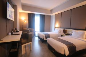 WonocoloBeSS Mansion Hotel Surabaya的酒店客房配有两张床和一张书桌