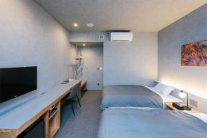 盛冈Hotel Mazarium的一间卧室配有两张床和一张书桌及电视