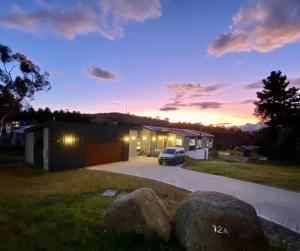 金德拜恩Jindabyne House 1, Modern 3 bedroom home, lake & mountain views with fireplace的日落时在车库前停车