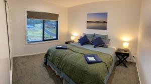 金德拜恩Jindabyne House 1, Modern 3 bedroom home, alpine views & fireplace的一间卧室设有一张大床和一个窗户。