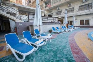 亚历山大AIFU Hotel El Montazah Alexandria的游泳池里的一组椅子和遮阳伞