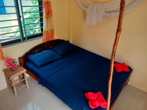 高龙撒冷岛Baloo Guesthouse的一间卧室配有一张蓝色床单和红色鲜花的床。