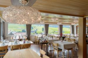 韦斯巴德Hotel Frohe Aussicht的餐厅设有白色的桌椅和大吊灯。