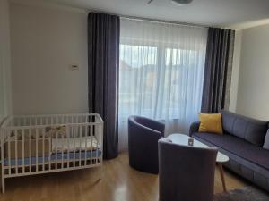 马汀Apartman centrum v súkromí的一间婴儿房,配有沙发和婴儿床
