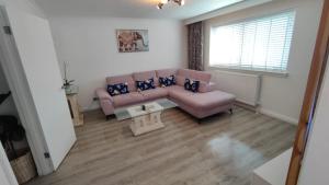 克莱德班克Lovely 2 Bedroom Modern Ground Floor Flat的客厅配有粉红色的沙发和桌子
