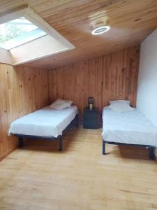 加普La marMotte perchée的配有木墙和窗户的客房内的两张床