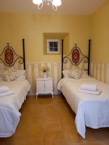 San RománCasa Rural Las Raíces, Sierra de San Vicente的黄色墙壁客房的两张床