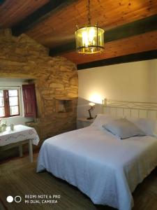 莫阿尼亚Casita en Domaio - Moaña的卧室配有白色的床和石墙