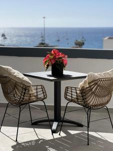 美洲海滩Boutique studio, sea views of Las Vistas and free wifi的一张桌子、两把椅子和一个花瓶,花上红色的花