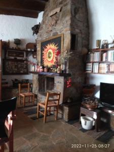 费内斯Eleni Country Cottage 2的石制壁炉,配有椅子和桌子