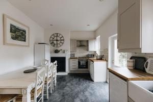 里彭HIGH SAINT COTTAGE - Stunning 3 Bed Accommodation located in Ripon, North Yorkshire的厨房配有白色橱柜和桌椅