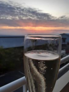 圣吉尔莱班BLUE SUMMER T3 - vue sur mer - Saint Gilles les Bains的坐在阳台上一边品尝葡萄酒一边欣赏日落美景
