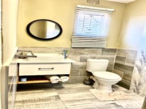 eMbalenhleEmba Guest lodge No loadshedding的一间带卫生间、水槽和镜子的浴室