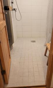 阿卡斯洛姆波罗Mäntymajat的带淋浴的浴室,铺有白色瓷砖地板。