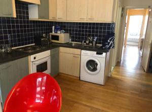 伦敦芬奇利路民宿的厨房配有洗衣机和红色椅子