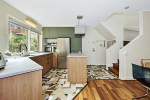 墨尔本Carlton Dream: Leafy 2bed 2bath Lygon Str Townhouse的一个带绿色橱柜和楼梯的厨房