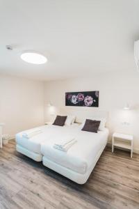 卡里翁德洛斯孔德斯Hostal Comfort Suites的铺有木地板的客房内一张大白色的床