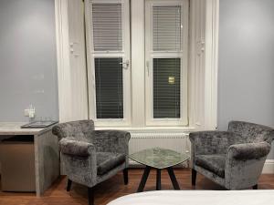 Laurieston Inn的带窗户的客房内配有两把椅子和一张桌子