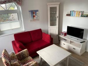 青斯特3-Zi-Ferienwohnung Piratennest 2的客厅配有红色沙发和电视