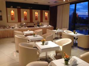 科莫蒂尼阿奇里奥酒店的一间设有白色桌子和白色椅子的餐厅和一间酒吧