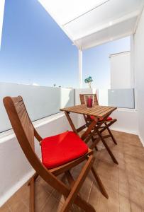 宏达海滩Luxury Beach Apartments Diama的一张木桌和椅子,配有红色靠垫