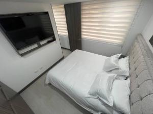 波哥大Aparta estudio central con ascensor 403的卧室内的白色床、枕头和电视