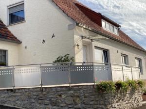 WehrHoliday apartment near the Moselle with terrace的白色的房子,有栅栏和石墙