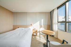 西归浦市Hotel Zinc的一间卧室配有一张床、一张书桌和一个窗户。