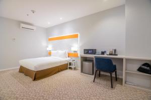 新山Holiday Inn Express & Suites Johor Bahru, an IHG Hotel的一间卧室配有一张床、一张桌子和一把椅子